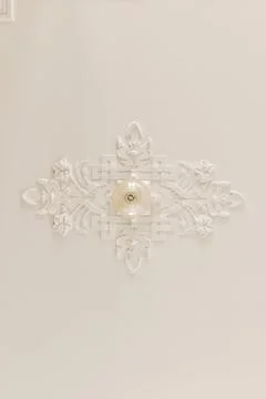 A white snowflake shaped ceiling fixture on a wall 스톡 사진
