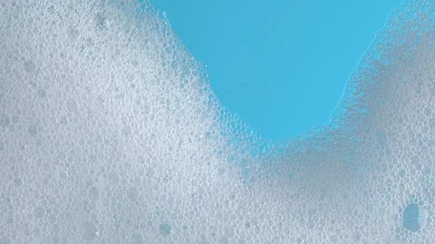 White soap suds flowing down window glass on blue background. Cleaning wind.. Stock Footage 269324757