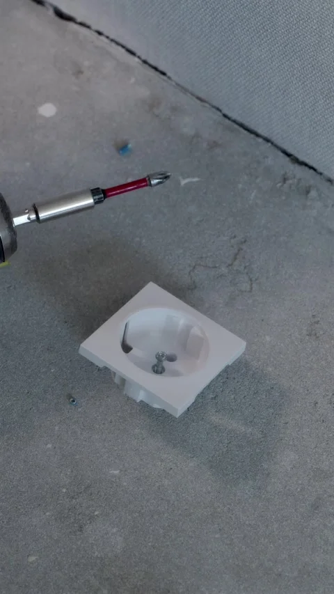 White socket cover plate and cordless screwdriver placed on concrete floor Video stock 345039467