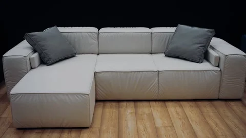 White sofa model with two gray pillows on a brown floor. Dark background. 4k Stock Footage 232055868
