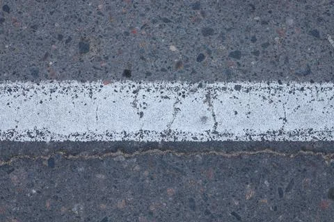 White solid dividing line on a textured dark asphalt road surface top view .. Stock Photos