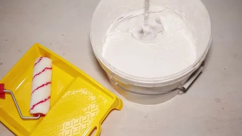 White solution is mixed with a large construction mixer in a white bucket Stock Footage 267095666