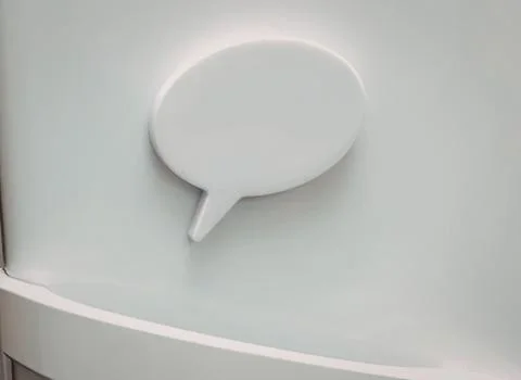 White speech bubble magnet on a smooth light surface Stock Photos