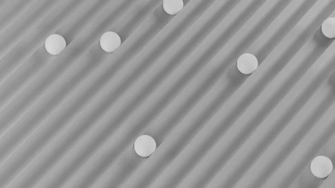 White spheres rolling on gray grooved surface animation Stock Footage 324490468