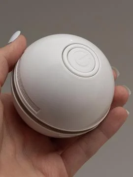 White spherical cat toy held in two hands Stock Photos