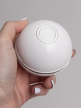 White spherical cat toy held in hands pressing button Stock Photos