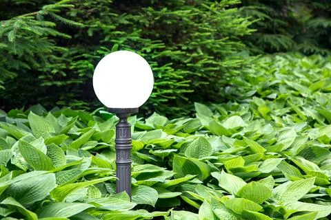 White spherical lantern on an iron pole of garden lighting. Stock Photos