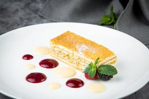 White sponge cake with drops of syrup, mint and wild berries on a round plate Stock Photos