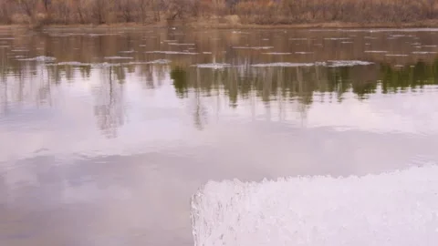 White spring ice lies on river bank, slowly melting into water The scene Video stock 278033284