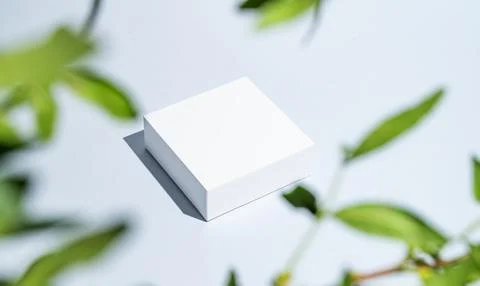 White square boxes on a blue background with shadows and green leaves. Stock Photos