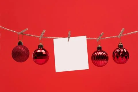 A white square piece of note paper hangs on clothespins on a red background Stock Photos