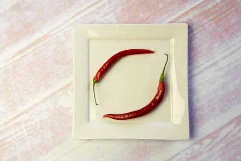White square plate with two red peppers Stock Photos