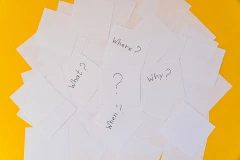White square sheets of paper with questions spread out in chaotic order on a  Stock Photos