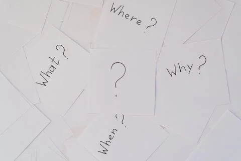 White square sheets of paper with questions spread out in chaotic order on a  Fotos de archivo