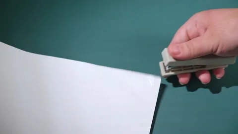 A white stapler in hand pierces many sheets of paper Stock Footage 239851928