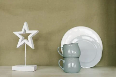 White star is on a shelf next to two cups and a white plate Stock Photos