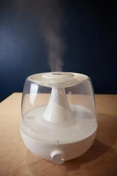 A white steam generator on the table stands running emits steam close up view Stock Photos