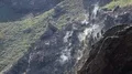 White steam rising up from under stones on rocky slopes sunny day, volcano HD Footage