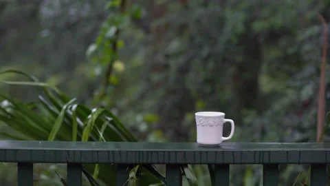 White steaming cup is on a green railing with jungle forest in background. Stock Footage 131055305