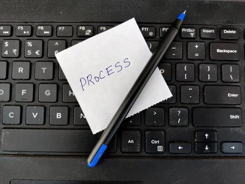 A White sticky note with text PROCESS and pen on top of laptop keyboard Stock Photos