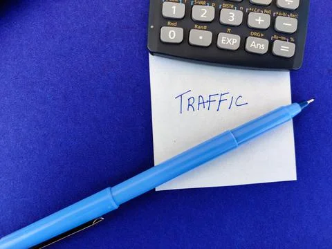 A White sticky note with text TRAFFIC kept under scientific calculator and pe Stock Photos