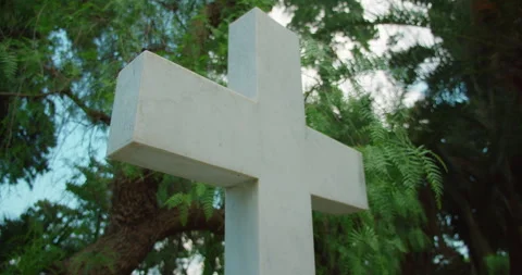 A white stone cross stands among lush summer greenery Stock Footage 345686932