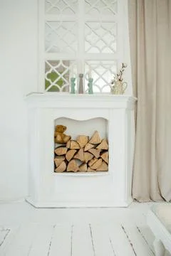 White stone fireplace with firewood without fire. Stock Photos