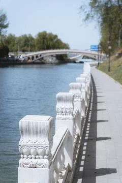 White stone railing along a riverside walkway with a bridge in the background Stock Photos