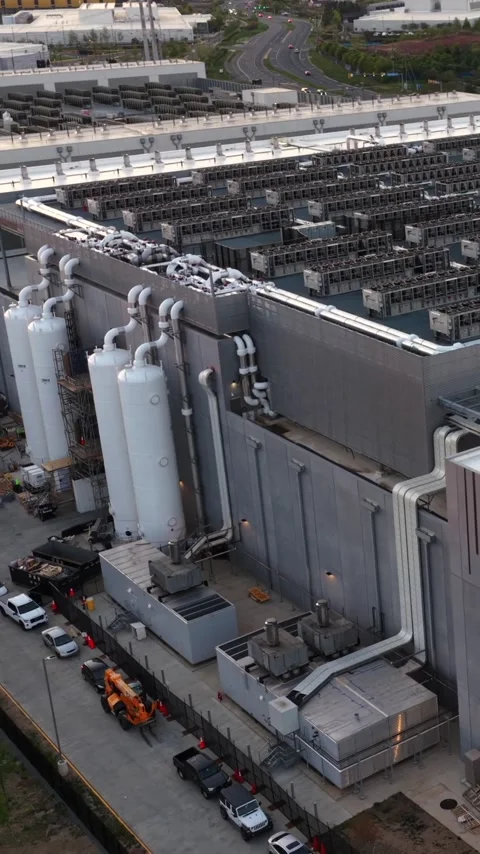 White storage tanks and switchgear stand against a data center hall in Ashburn Stock Footage 345728225