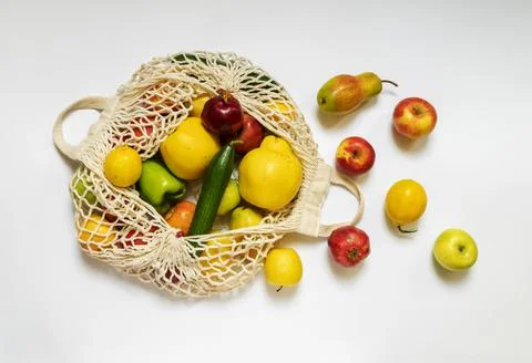 White string bag with different vegetables and fruits on a white background.  Stock Photos