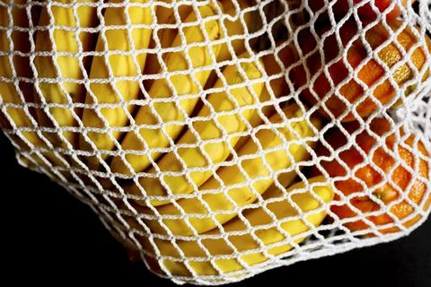 White string mesh bag filled with fruit isolated on a black background Foto stock