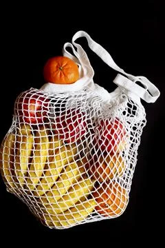White string mesh bag filled with fruit isolated on a black background Foto stock