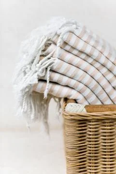 White stripe cotton towels in whicker basket against white wall. Stock Photos