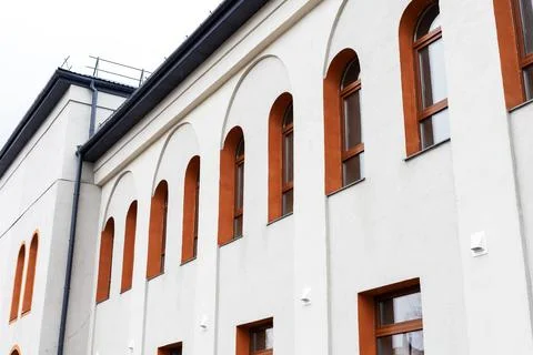 White stucco facade with arched windows, terracotta frames catching warm sunl Stock Photos