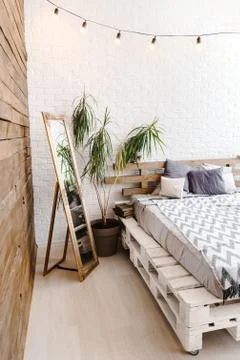 White studio interior with pallets bed, mirror and lamps Stock Photos
