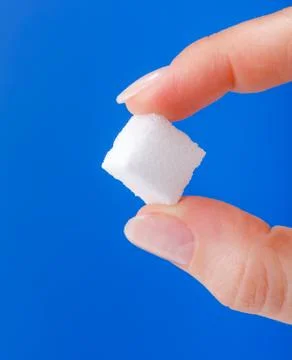 White sugar cube held between fingers Stock Photos