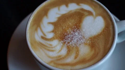 White sugar falling over cappuccino milk foam and dissolving Video stock 84837011
