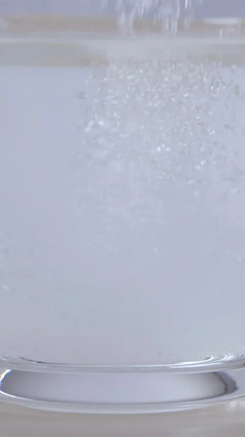 White Sugar Granules Pouring and Dissolving in Glass of Water Stock Footage 343603660