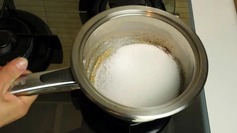 White sugar in a pot is heated with fire until it becomes caramel. Video 4K Video stock 238917689