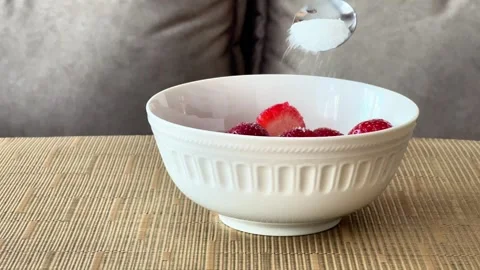 White Sugar Pouring from Spoon Onto Sliced Red Strawberries inside Ceramic Bowl Видео 336936294