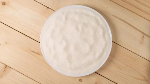 White sugar rotating on a wooden table top view Stock Footage 338312357