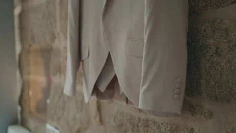 White suit jacket hanging against stone wall indoors Stock Footage 324885769