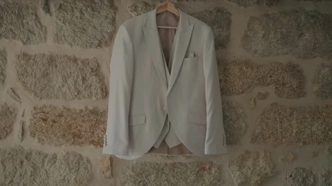 White suit jacket hanging on stone wall Stock Footage 324885701