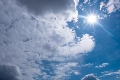 White sun with clouds on blue sky Stock Photos
