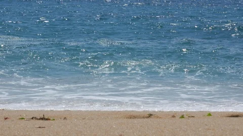 White surf waves breaking on sandy beach with bright sunlight glinting on water. Stock Footage 111706363