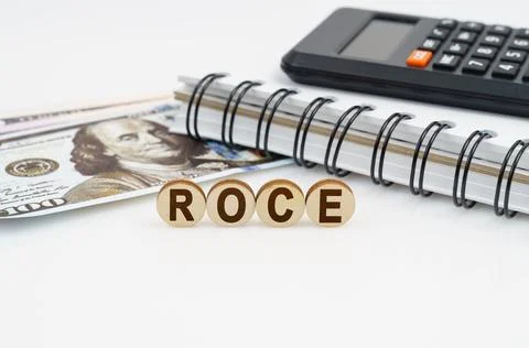 On a white surface are dollars, a notebook, a calculator and wooden circles w Stock Photos
