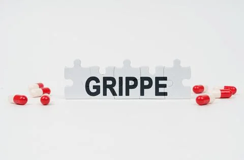 On a white surface are tablets and puzzles with the inscription - Grippe Stock-Fotos