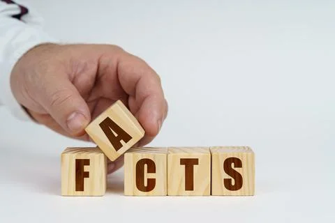 On a white surface, a man stacks cubes with the inscription - FACTS Stock Photos