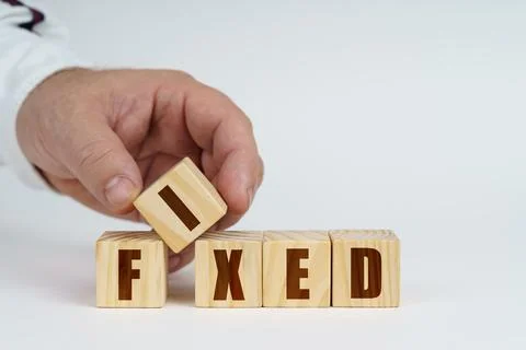 On a white surface, a man stacks cubes with the inscription - FIXED Stock Photos