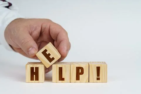 On a white surface, a man stacks cubes with the inscription - HELP Stock Photos